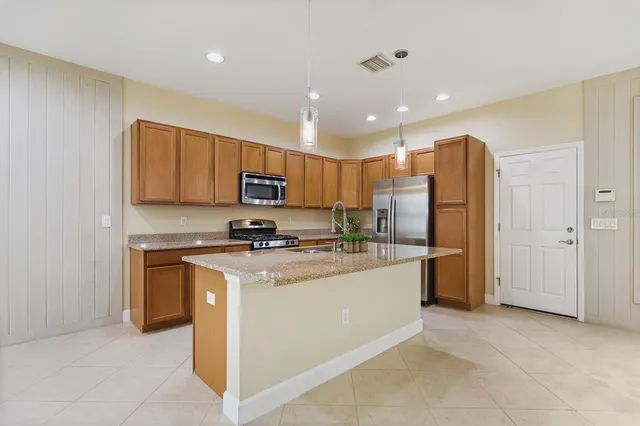 a kitchen with stainless steel appliances granite countertop a stove top oven a refrigerator a sink and a microwave