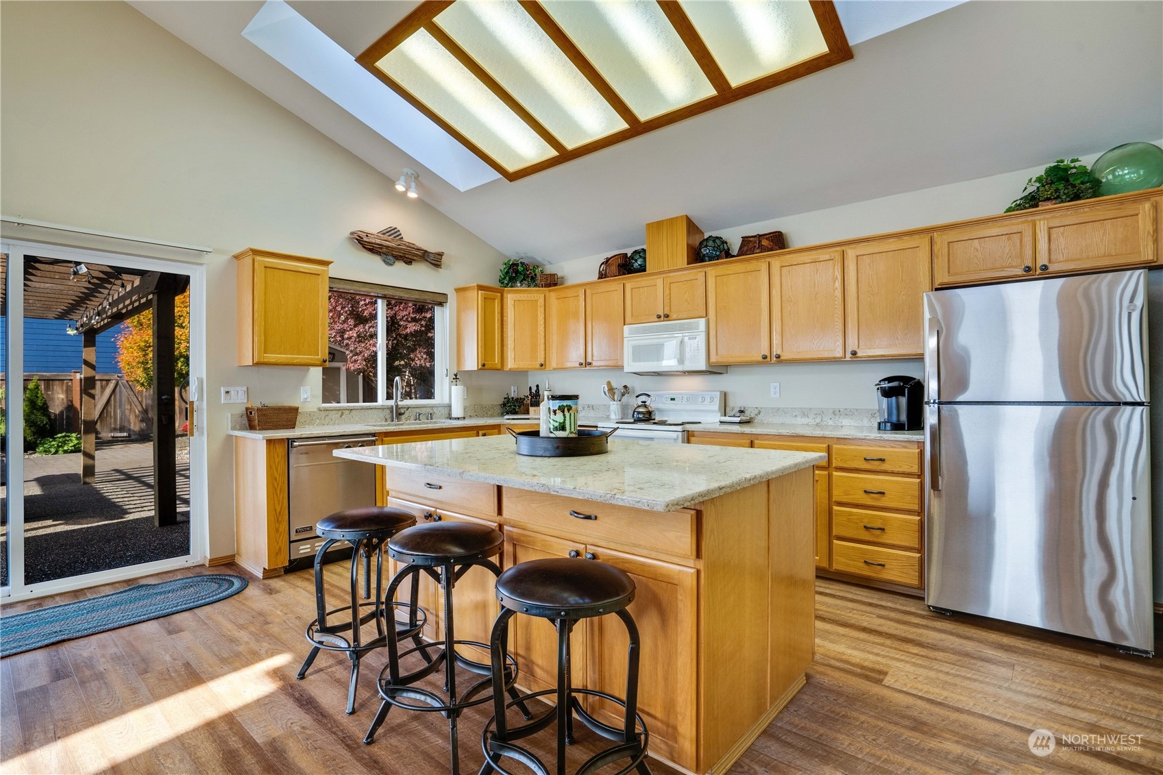 7381 Northeast North Shore Road Belfair, WA 98528 - Photo 10 of 38 a kitchen with stainless steel appliances granite countertop a refrigerator a stove a sink dishwasher and white cabinets with wooden floor