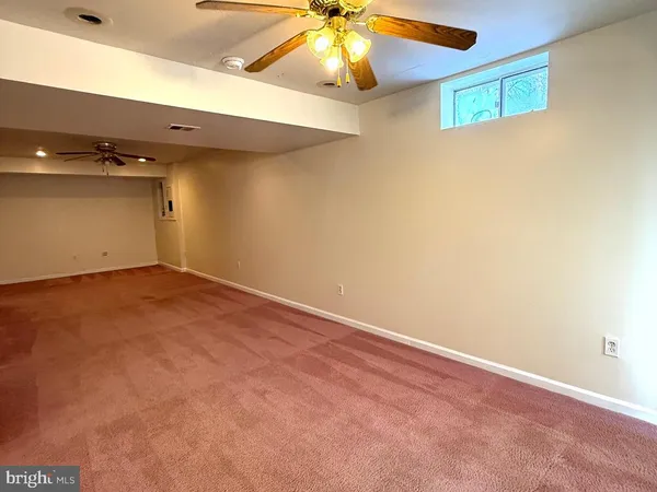an empty room with a ceiling fan and carpet