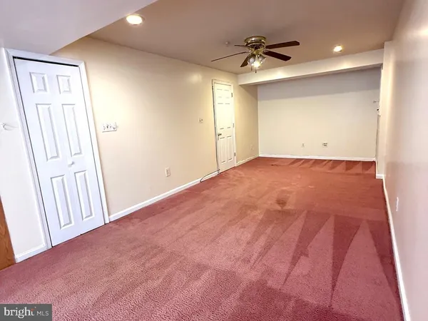 an empty room with a ceiling fan and a rug
