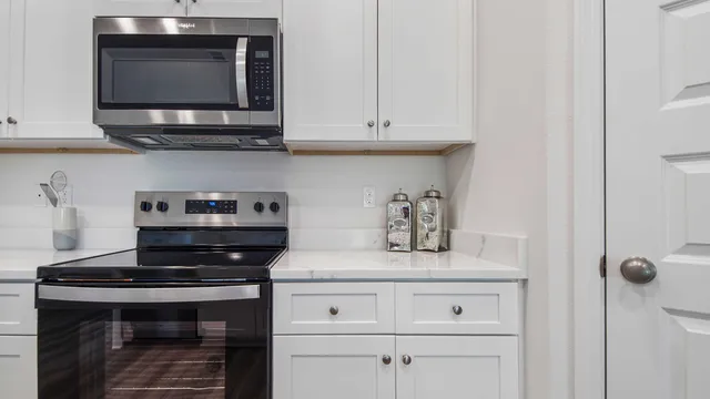 a kitchen with stainless steel appliances granite countertop white cabinets and a stove a oven with white countertops