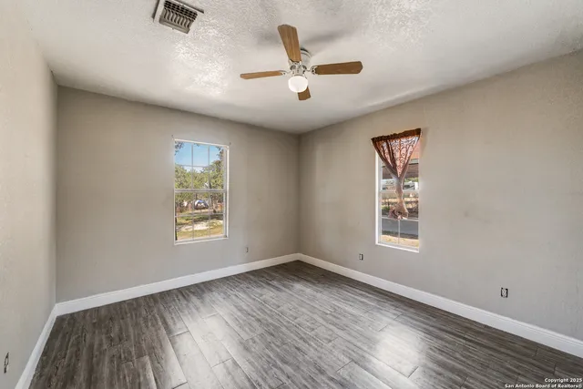 a view of an empty room with a window and wooden floor