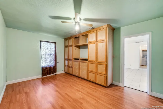 an empty room with wooden floor cabinet and windows