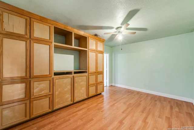an empty room with wooden floor fan and windows