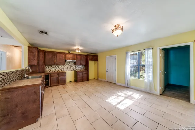 a view of a kitchen with kitchen island granite countertop a sink cabinets and stainless steel appliances