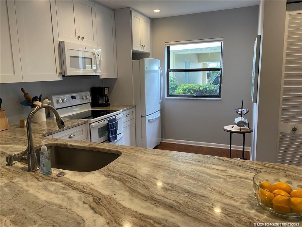 3901 Southeast St Lucie Boulevard, Unit D29 Stuart, FL 34997 - Photo 10 of 26 a kitchen with stainless steel appliances granite countertop a sink stove and refrigerator