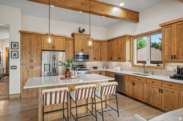 4892 Eagle Rdg Drive Eden, UT 84310 - Photo 13 of 39 Kitchen featuring natural wood cabinetry, a large central island with seating, stainless steel appliances, a tile backsplash, and wood-finish flooring