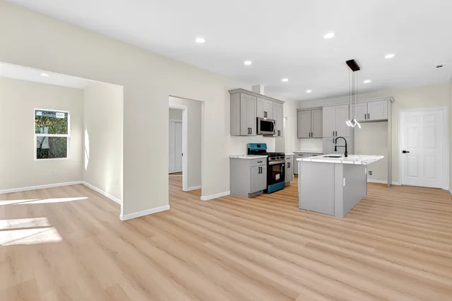 a view of a kitchen with kitchen island a sink wooden floor and a refrigerator