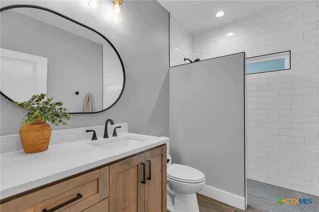 a bathroom with a sink a toilet a mirror and shower