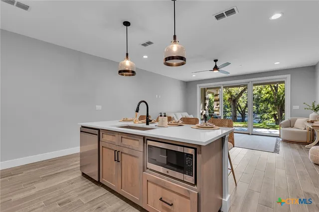 a kitchen with a stove a sink a window and chairs