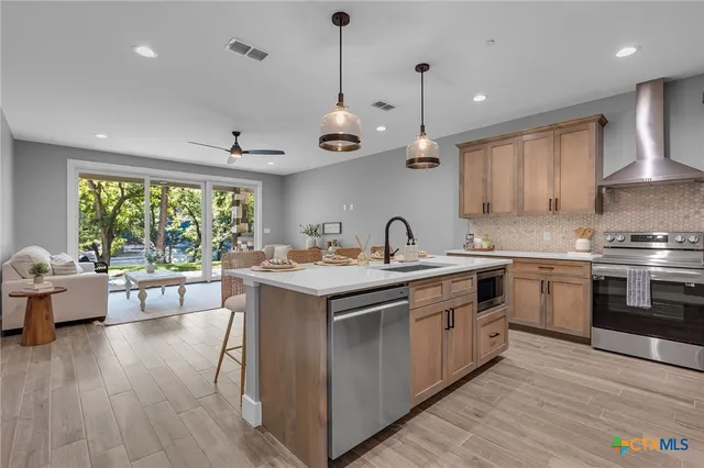 a kitchen with a stove a sink a kitchen island with wooden floor and cabinets