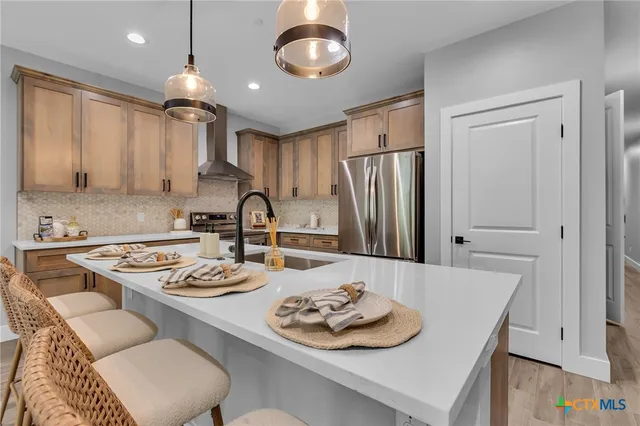 a kitchen with stainless steel appliances granite countertop a sink stove and refrigerator with wooden floor