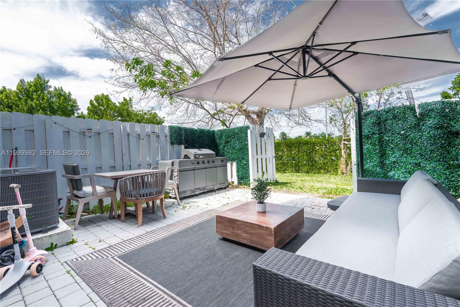 9949 Southwest 228th Terrace Miami, FL 33190 - Photo 1 of 40 a view of a patio with a dining table and chairs under an umbrella