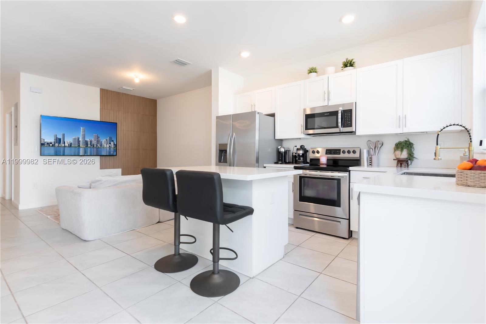9949 Southwest 228th Terrace Miami, FL 33190 - Photo 4 of 40 a kitchen with stainless steel appliances kitchen island granite countertop a sink a stove a dining table and chairs