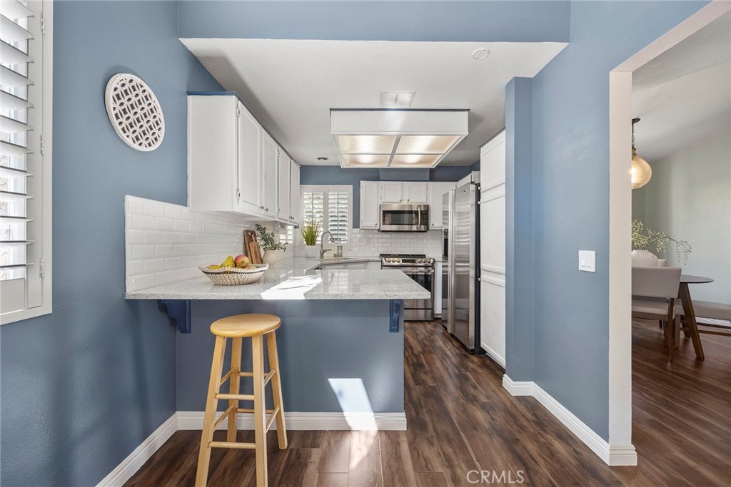5370 Silver Canyon Road, Unit 7E Yorba Linda, CA 92887 - Photo 20 of 33 a kitchen with stainless steel appliances a dining table chairs and wooden floor
