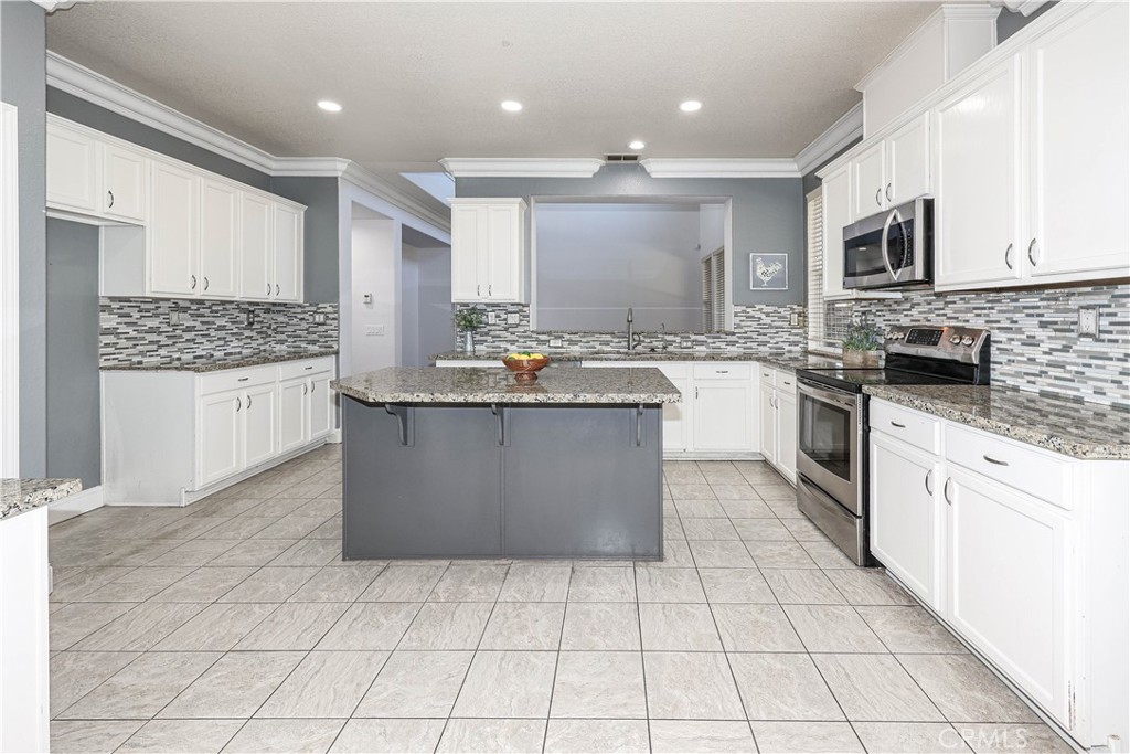 1367 Esplanade Drive Merced, CA 95348 - Photo 13 of 51 a kitchen with stainless steel appliances granite countertop a stove top oven a sink a counter top space and cabinets