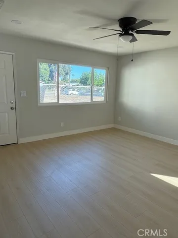 an empty room with wooden floor ceiling fan and windows