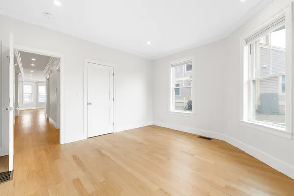 a view of empty room with wooden floor and fan