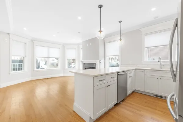 a large kitchen with cabinets wooden floor and a window