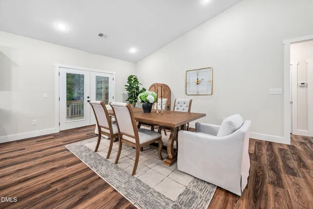 a kitchen with stainless steel appliances granite countertop a sink dishwasher and a dining table with wooden floor