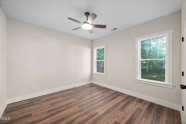 a view of an empty room and chandelier fan