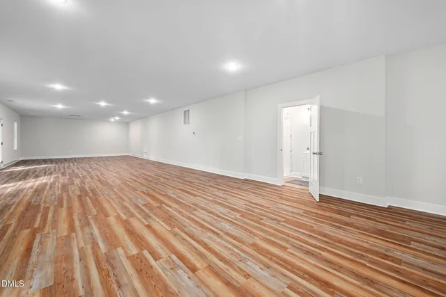 an empty room with wooden floor and entrance