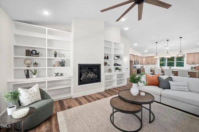 a view of a room with wooden floor chandeliers and kitchen view
