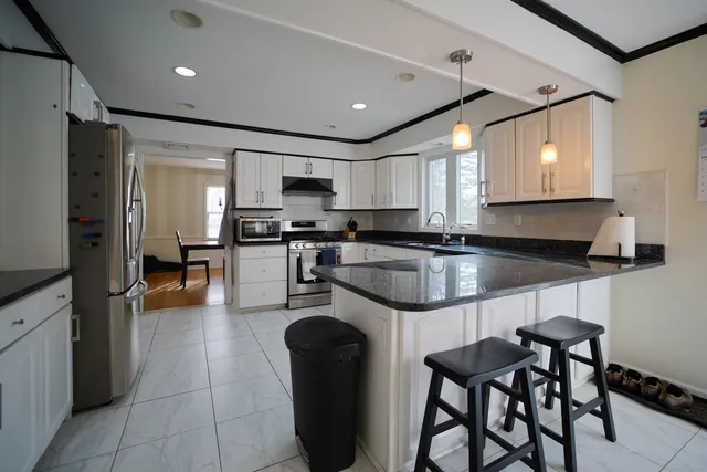 a kitchen with stainless steel appliances granite countertop a refrigerator a sink a stove a dining table and chairs