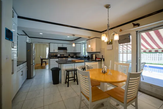 a kitchen with stainless steel appliances granite countertop a refrigerator a sink dishwasher a dining table and chairs with wooden floor