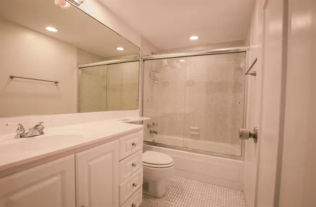a bathroom with a shower sink vanity mirror and toilet