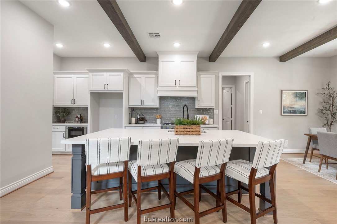 13291 Hopes Creek Road College Station, TX 77845 - Photo 3 of 45 Kitchen featuring backsplash, white cabinets, recessed lighting, a breakfast bar area, and beamed ceiling