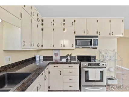 a kitchen with granite countertop a sink a stove and cabinets