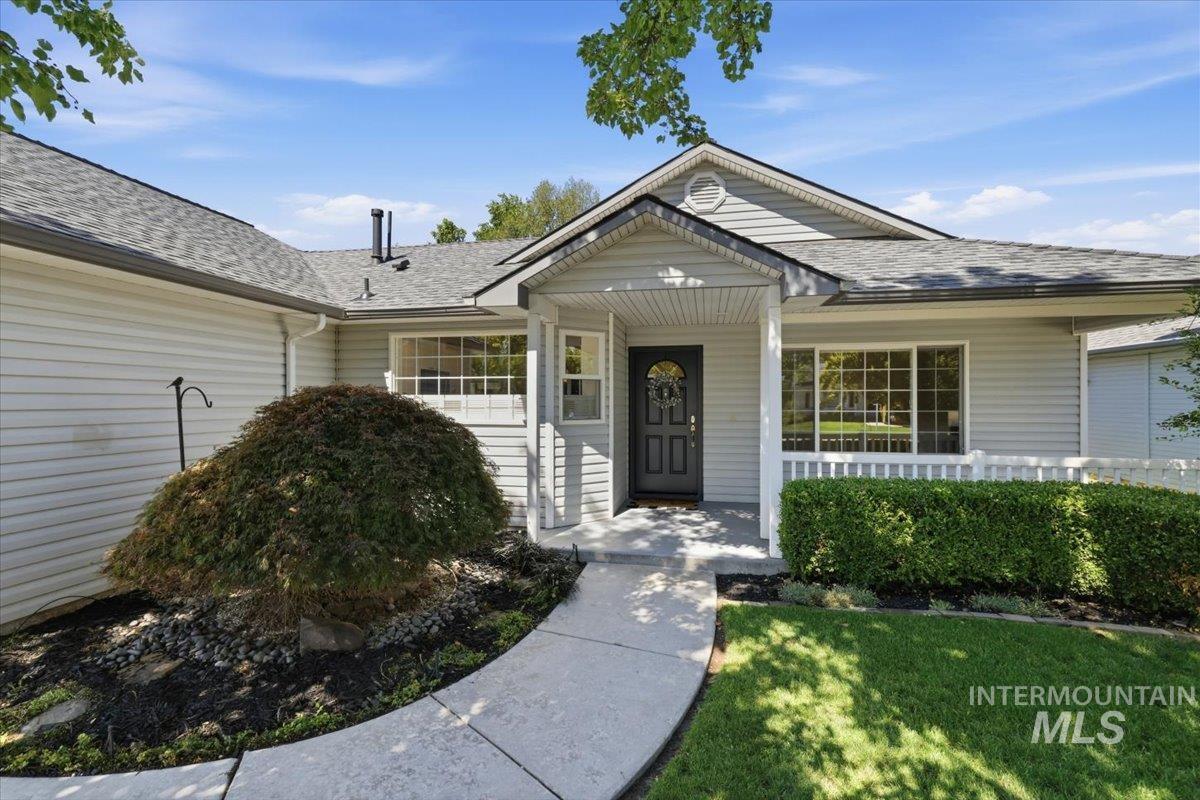 2075 North Springland Place Boise, ID 83713 - Photo 5 of 49 Welcoming entry featuring a covered porch with a dark-paneled front door, flanked by a white railing and manicured hedges