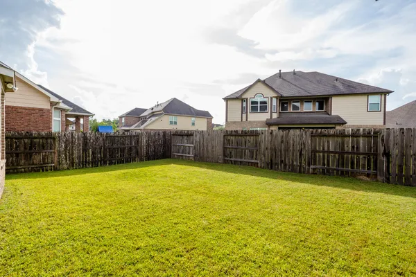 a view of a house with wooden fence and a yard