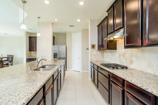 a kitchen with granite countertop stainless steel appliances a sink stove top oven and cabinets