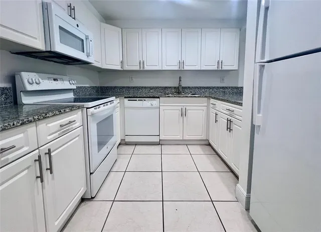 a kitchen with granite countertop white cabinets and white appliances