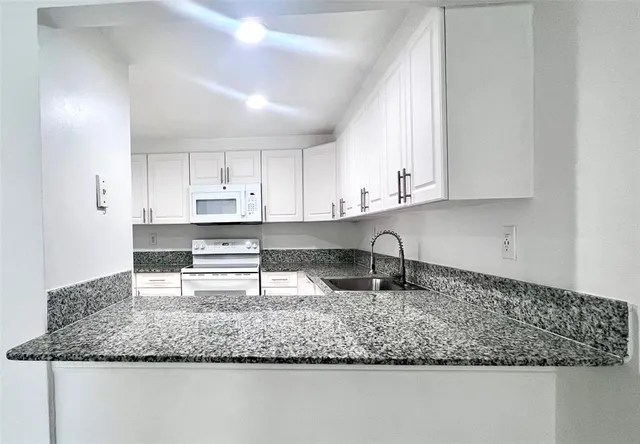 a kitchen with granite countertop a sink a stove and cabinets