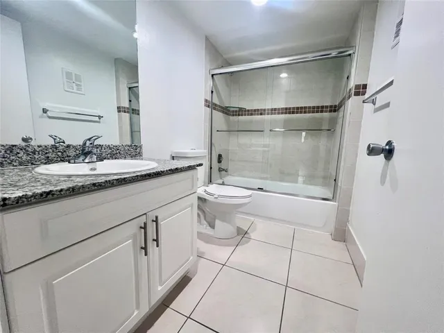 a bathroom with a granite countertop sink mirror vanity and toilet