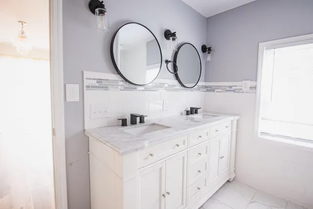 a bathroom with a granite countertop double vanity sink and a mirror