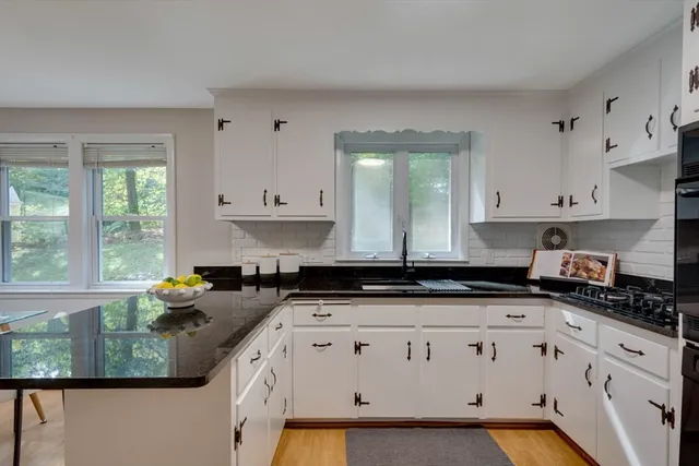 a kitchen with granite countertop a sink a stove a cabinets and a window