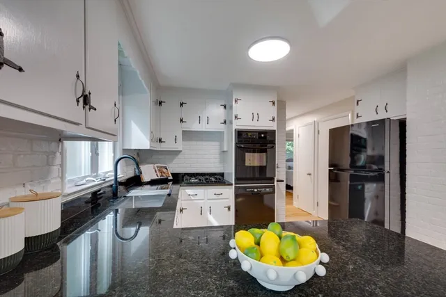 a kitchen with granite countertop a sink stainless steel appliances and cabinets
