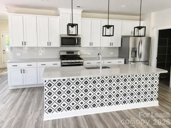 a kitchen with stainless steel appliances a sink a stove a refrigerator cabinets and a wooden floor