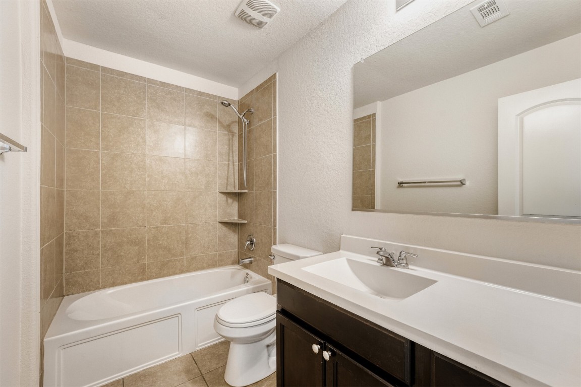 433 Druse Lane Jarrell, TX 76537 - Photo 26 of 28 Bathroom with vanity, tub / shower combination, a textured wall, a textured ceiling, and light tile patterned floors