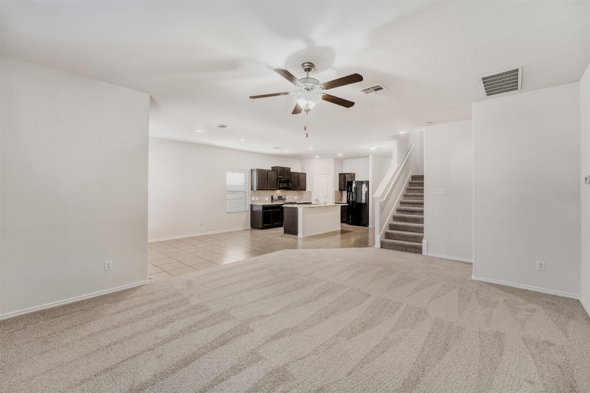433 Druse Lane Jarrell, TX 76537 - Photo 7 of 28 Unfurnished living room with light carpet, stairway, a ceiling fan, light tile patterned flooring, and recessed lighting