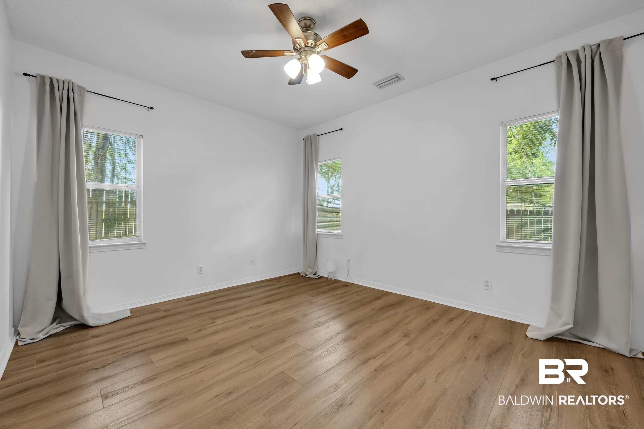 17488 Pandion Ridge, Unit A1 Fairhope, AL 36532 - Photo 12 of 18 Spacious room featuring wood-finish flooring, white walls, and a ceiling fan with light fixture