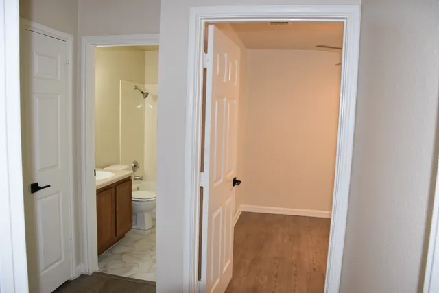 an empty room with a chandelier fan and windows