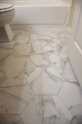 an empty room with wooden floor chandelier fan and windows