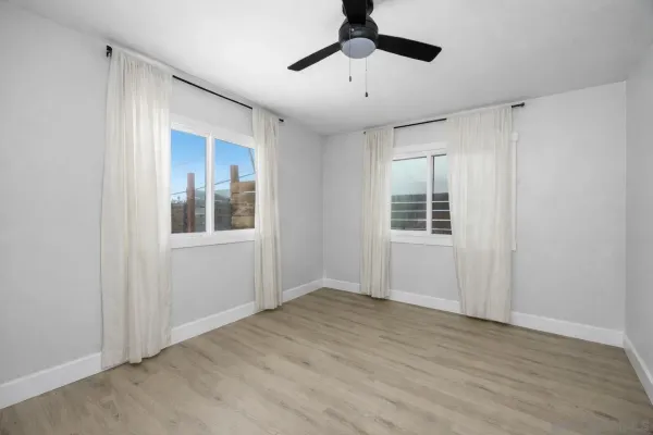 a view of empty room with wooden floor and fan