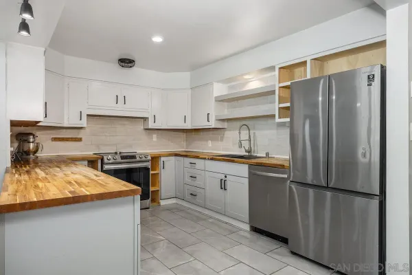 a kitchen with stainless steel appliances granite countertop a refrigerator a sink and white cabinets