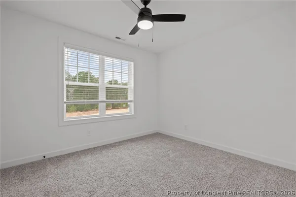 an empty room with a window and a fan
